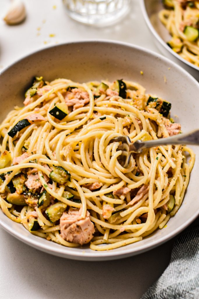 Fork twirling up noodles from the bowl with tuna zucchini pasta.