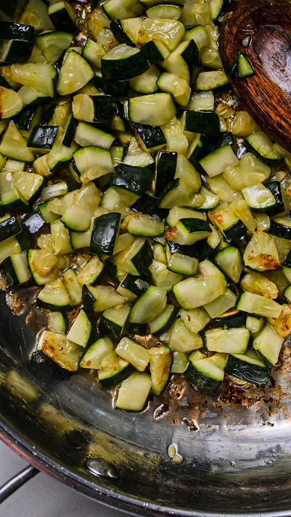 Cooking the diced zucchini in a large pan.