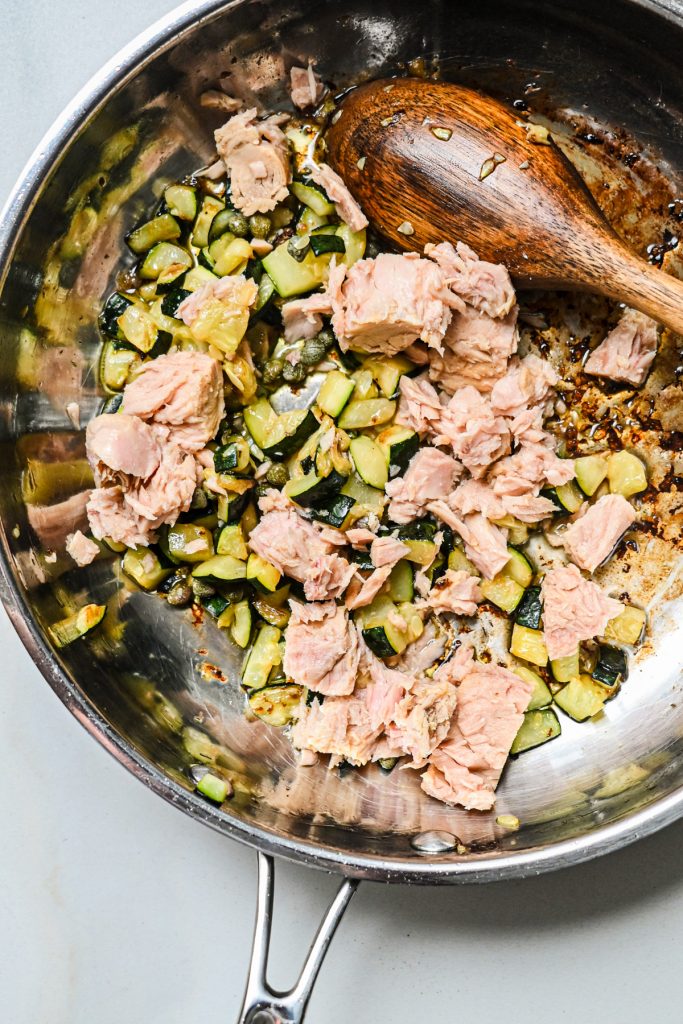 Adding the tuna into the pan with the cooked zucchini.