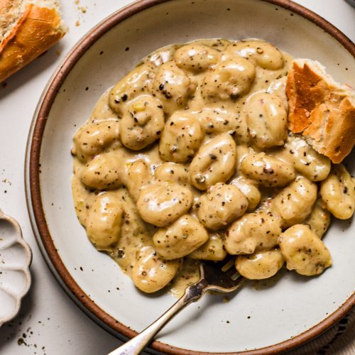 Creamy gnocchi au poivre served in a bowl with freshly cracked pepper on top.