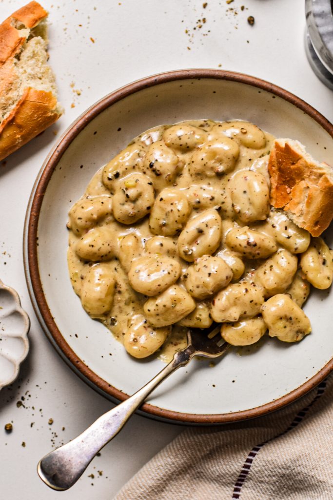 Creamy gnocchi au poivre served in a bowl with freshly cracked pepper on top.