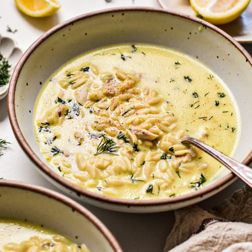 Creamy chicken orzo yogurt soup in a soup bowl with a spoon.