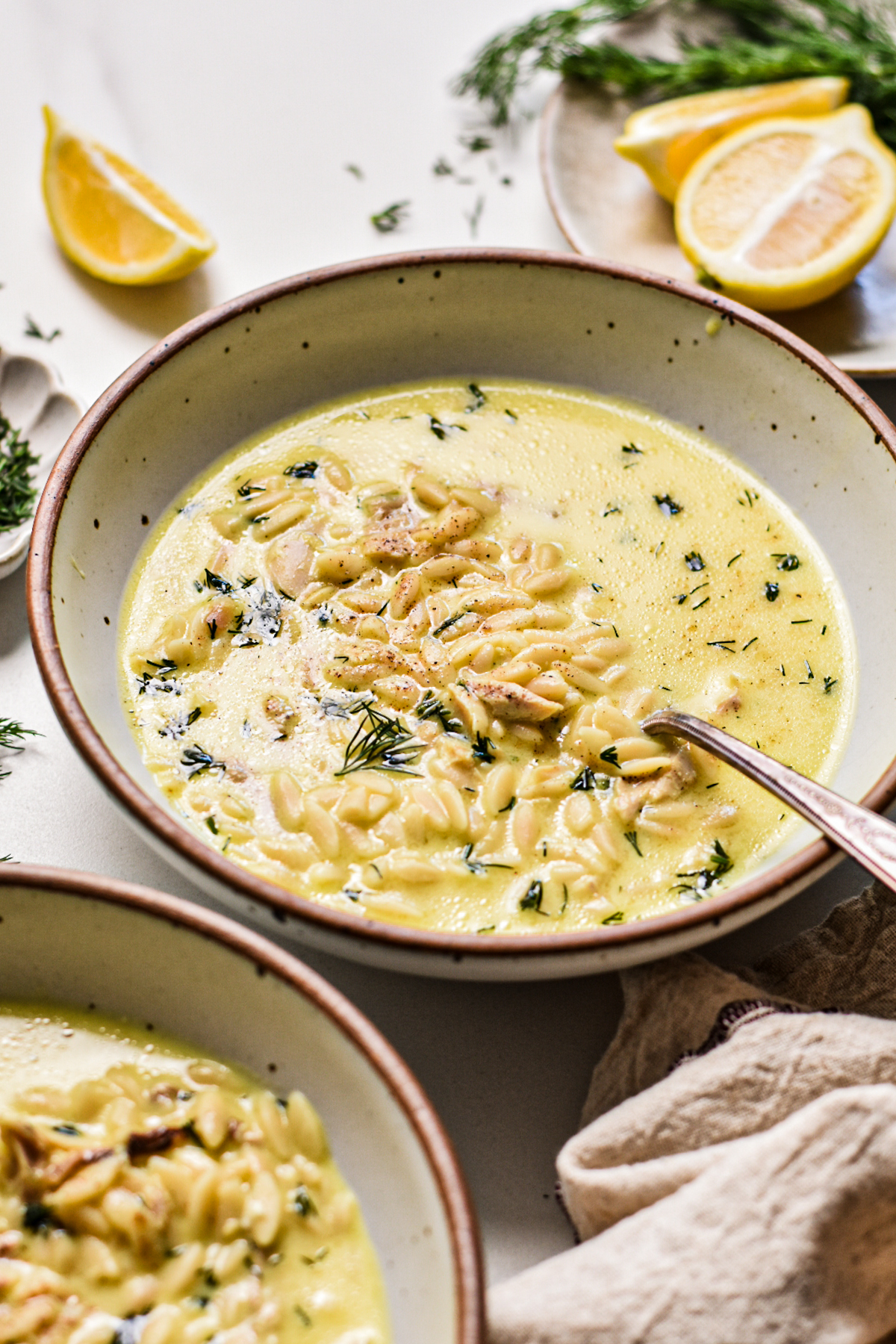 Creamy chicken orzo yogurt soup in a soup bowl with a spoon.