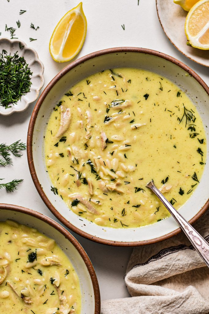 Overhead shot of chicken orzo yogurt soup garnished with fresh dill.