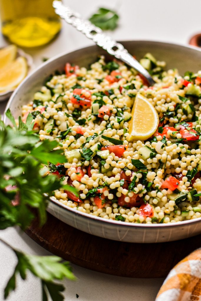 Side view of acini di pepe tabouleh salad in a shallow serving bowl.