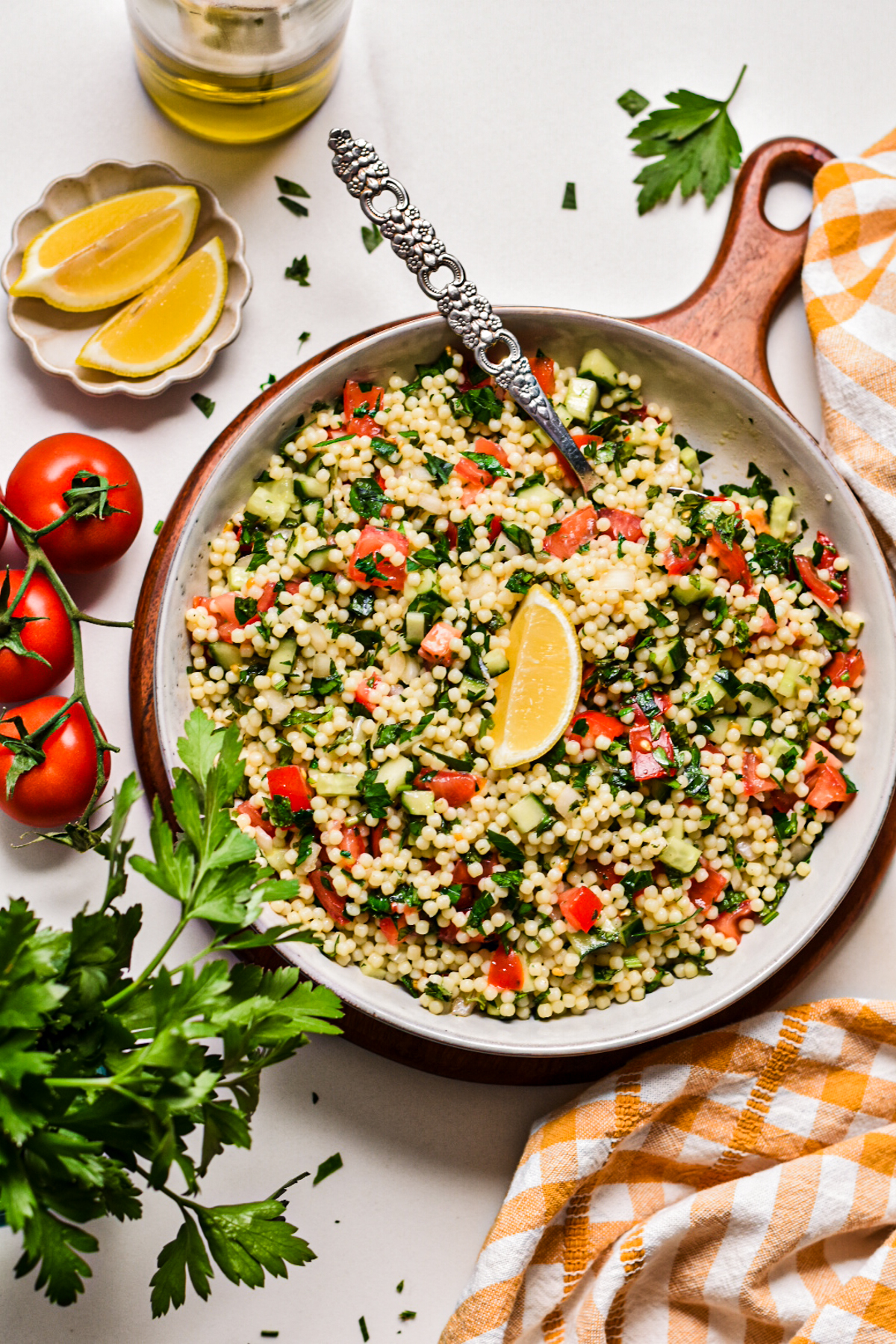 Acini di pepe tabouleh salad in a bowl topped with a lemon wedge.