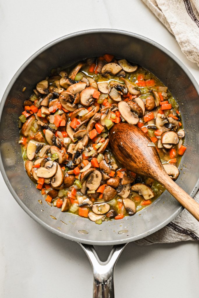 Cooked vegetables in the pot with a wooden spoon.