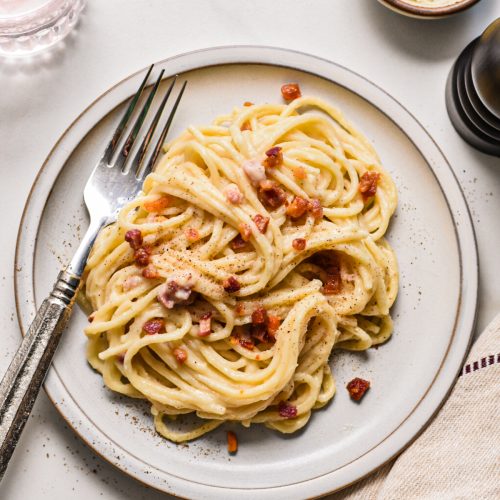Overhead shot of creamy pancetta cauliflower pasta served on a plate with a fork.