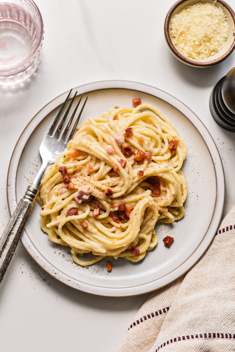 Overhead shot of creamy pancetta cauliflower pasta served on a plate with a fork.