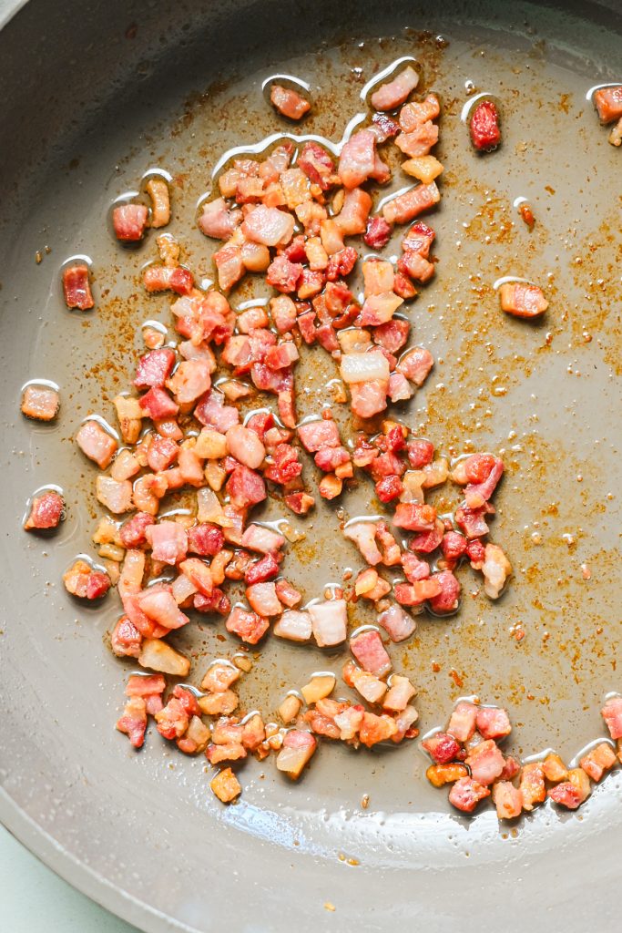 Pancetta cooking in a skillet.
