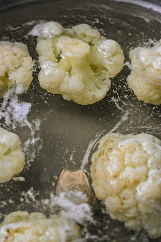 Cauliflower florets boiling in a pot of water.
