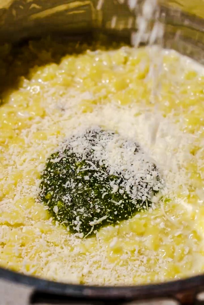 Adding freshly grated parmesan cheese to the pastina pasta.