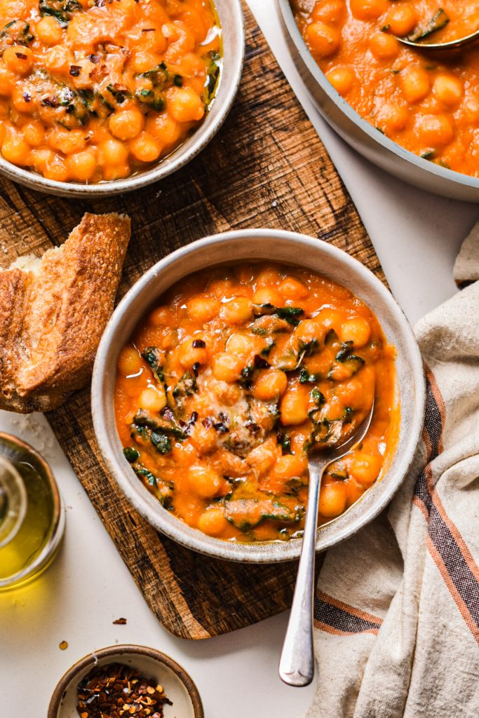 Overhead shot of a bowl of fennel tomato gnocchi soup with crust bread on the side.
