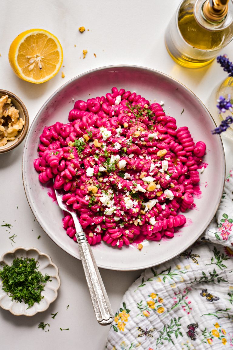 Overhead shot of creamy chickpea beet pasta with feta in a shallow bowl.