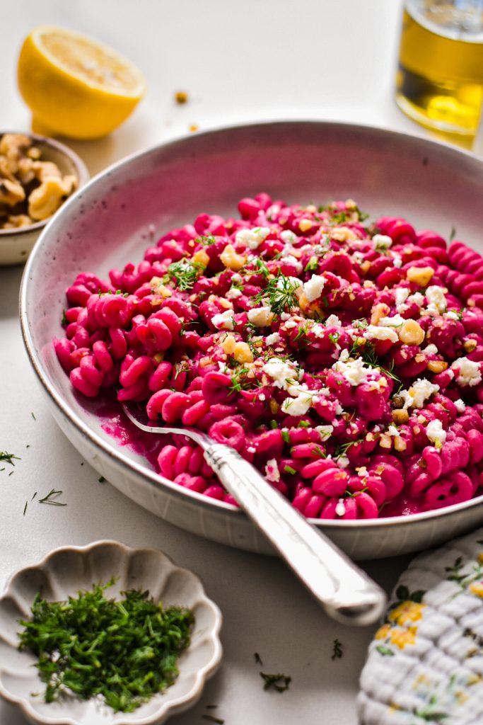 Side view of creamy chickpea beet pasta with feta in a shallow bowl.