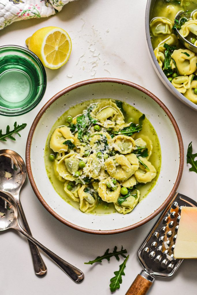 Spring tortellini in brodo served in a bowl with parmesan on top.