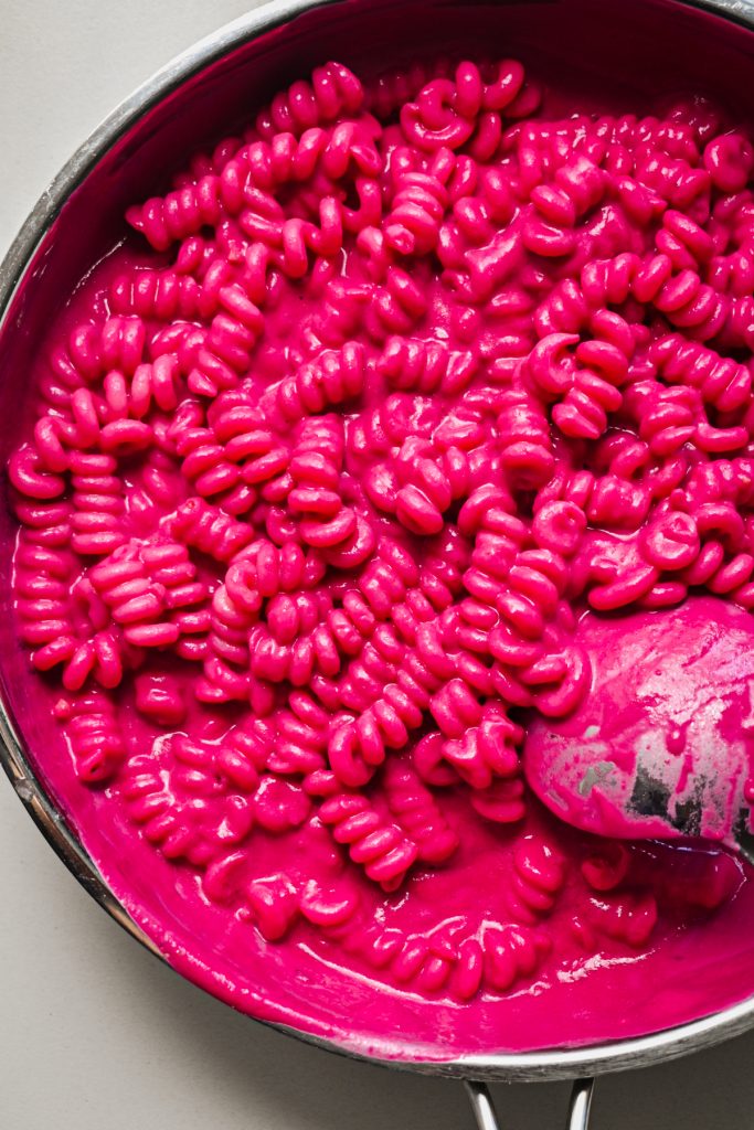 Cooked pasta tossed with the beet pasta sauce in a skillet.
