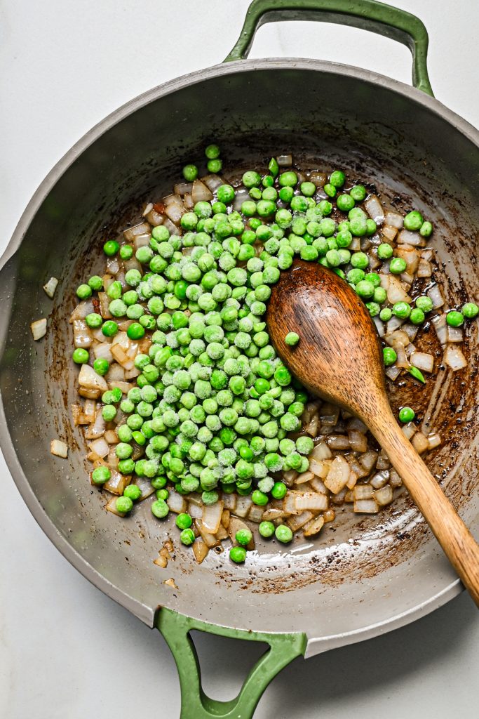 Peas and onions added to the skillet to sauté.
