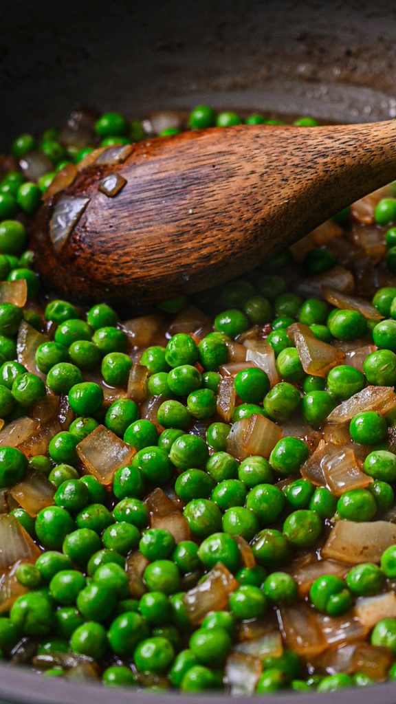 Close up of bacon and onions cooking in a skillet.
